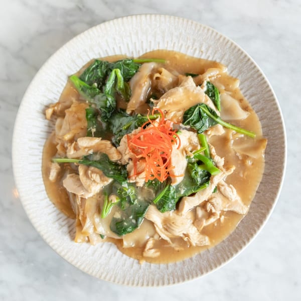 Phattra Thai Restaurant's chicken and spinach noodles in a savory sauce, topped with shredded carrots.